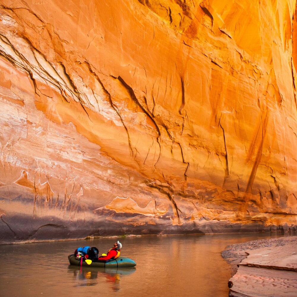 kayaker peering up at a canyon wall in a slot canyon